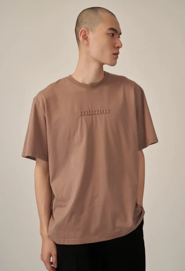 Front view of man wearing sand recycled pet t-shirt with embossed logo in studio setting