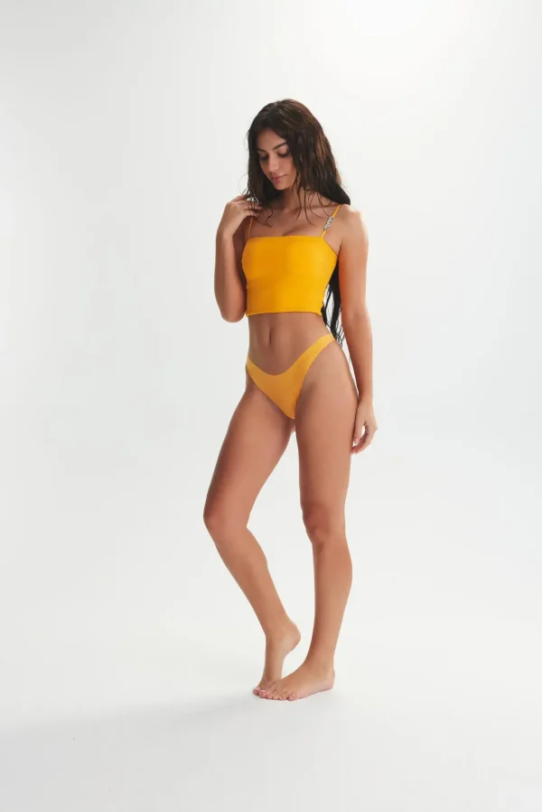 Model wearing orange shining bra top with matching bikini bottoms