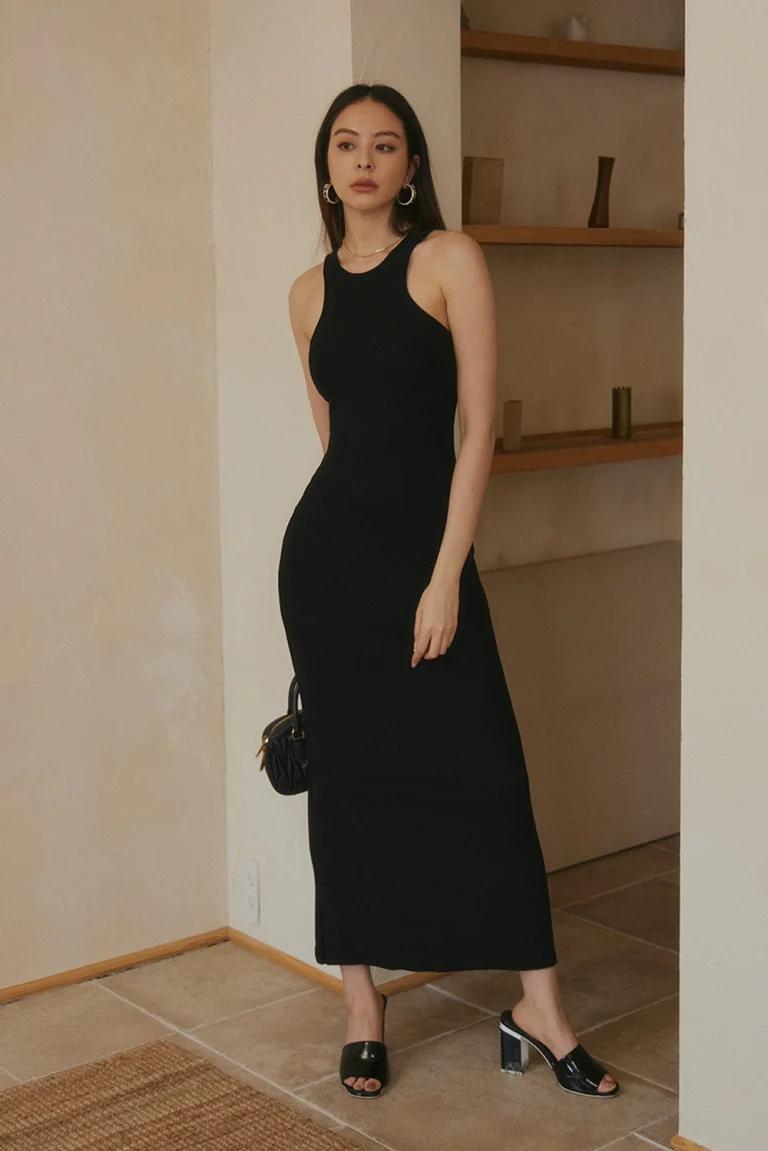 A female model wearing black Elegant Rib-knit Halter Maxi Bra Dress with heels and handbag